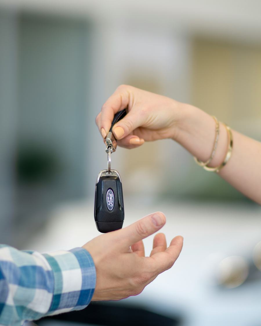 A seller handing a car key to a buyer
